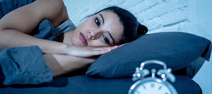 woman in bed looking at clock